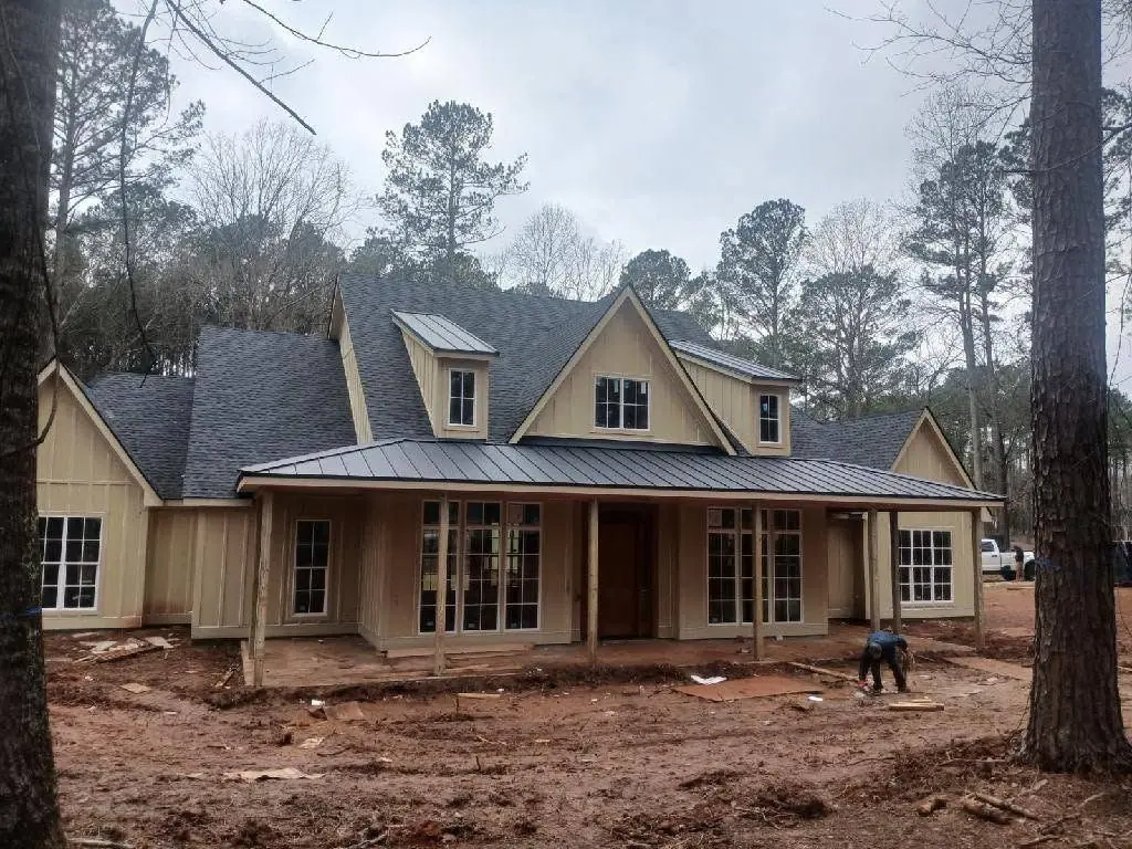 Finished custom home with shingle roof and standing seam metal porch roof