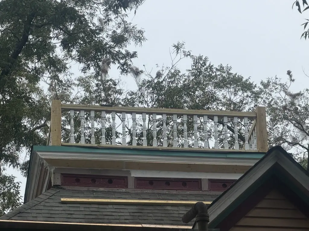 New turned balusters and railing rebuilt on the roof of the older home