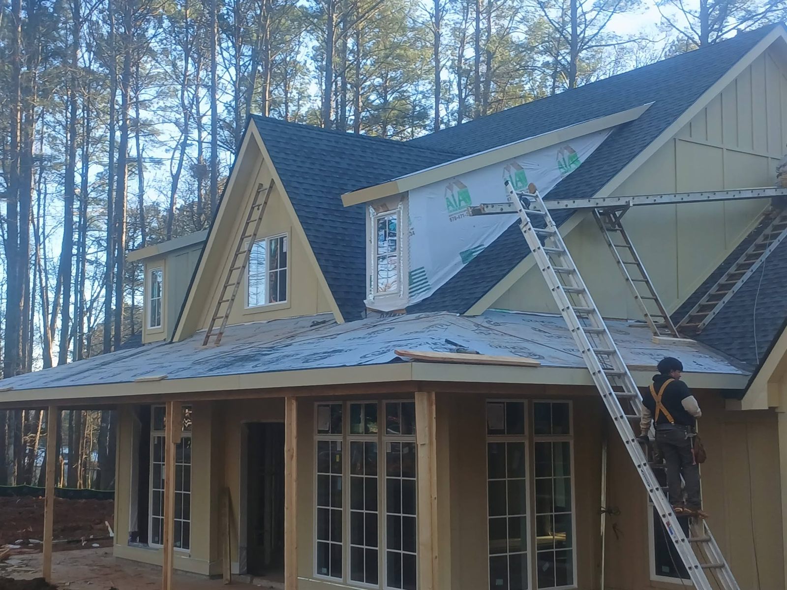 Roofing crew member working in a safety harness on a new construction roof